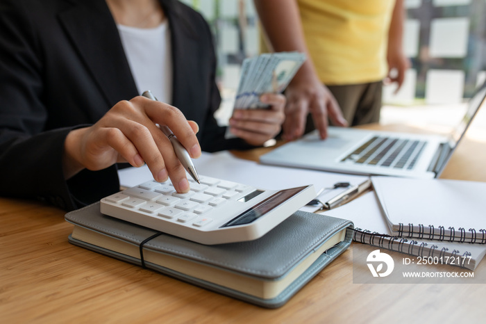 Savings, finances, economy and home concept - close up of businesswoman with calculator counting money and making notes at home office