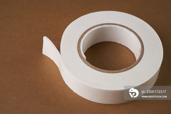 White double sided tape on light-brown background with copy space.Close up.