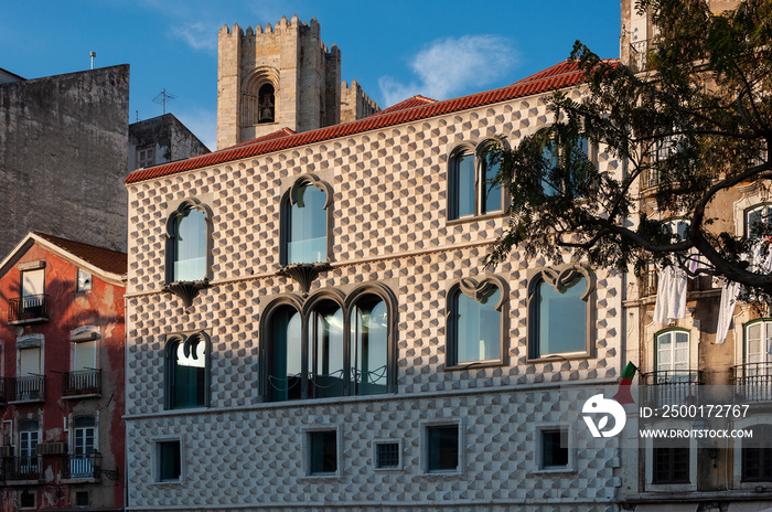 The Casa dos Bicos at the Campo das Cebolas, with the bell tower of the Lisbon Cathedral on the background, in the city of Lisbon, Portugal