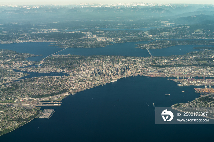 Elliot Bay (Washington) with aerial city view of landscape around Seattle Downtown and Seattle suburbs located around central city with mountains and lakes in the background