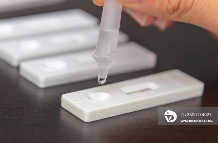 Man performing a self test. Rapid antigen diagnostic test kit with nasal swab and tube.