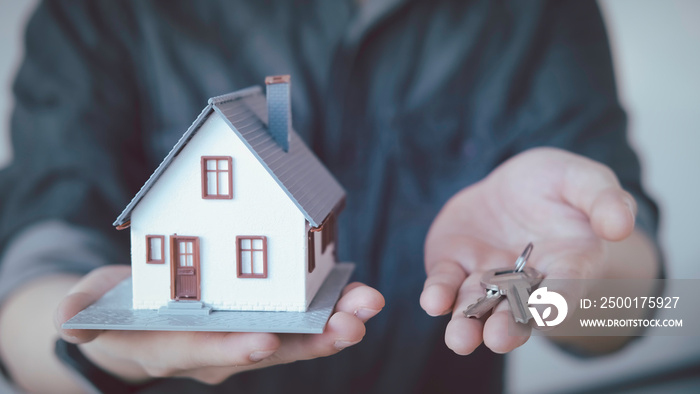 Hands holding small house after signing contract,concept for real estate,Insurance and safety concept with house protected by hands, moving home or renting property