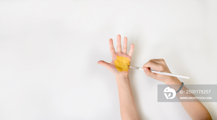 Close up photo of child who paint his hand with yellow paint