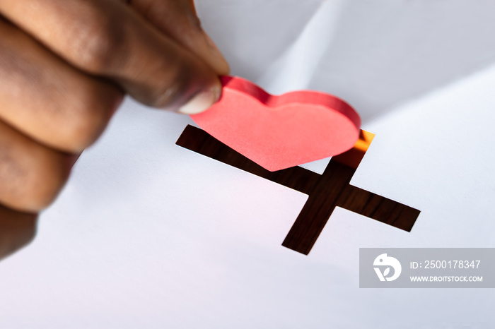 Man Inserting Heart Shape In Crucifix Slot