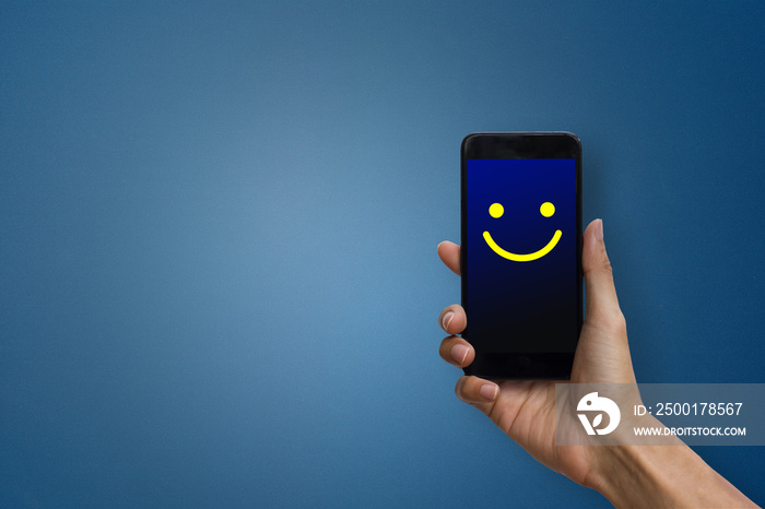 Conceptual the customer responded to the digital survey. The client showing mobile phone screen with happy face. Depicts that customer is very satisfied. Service experience and satisfaction concept.