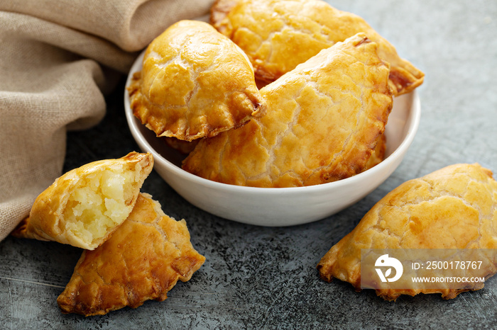 Hand pies, pasties, samosas or pierogies with potato filling golden baked