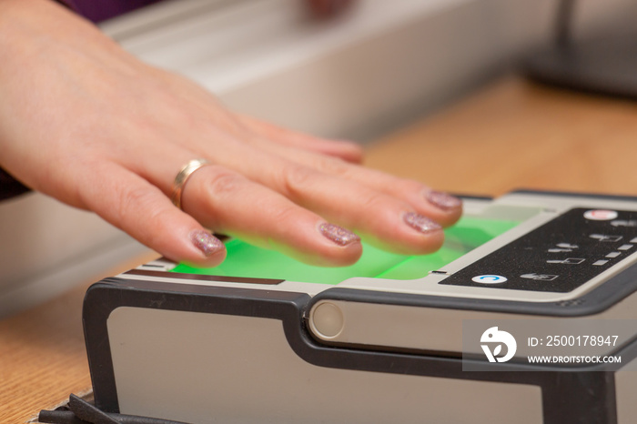 The process of scanning fingerprints during the check at border crossing. Female hand puts fingers to the fingerprint scanner. Identity verification and border control, immigration concept