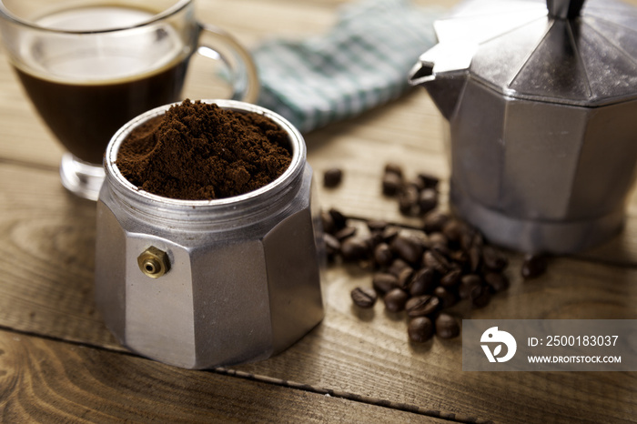 Italian coffee maker with napkin and cup of coffee on table