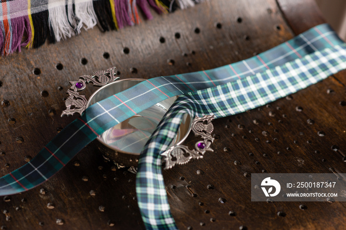 quaich with tartan ribbon on wooden bench