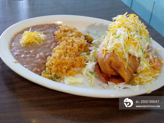 Chimichanga covered in sour cream, Cheese, lettuce and tomatoes