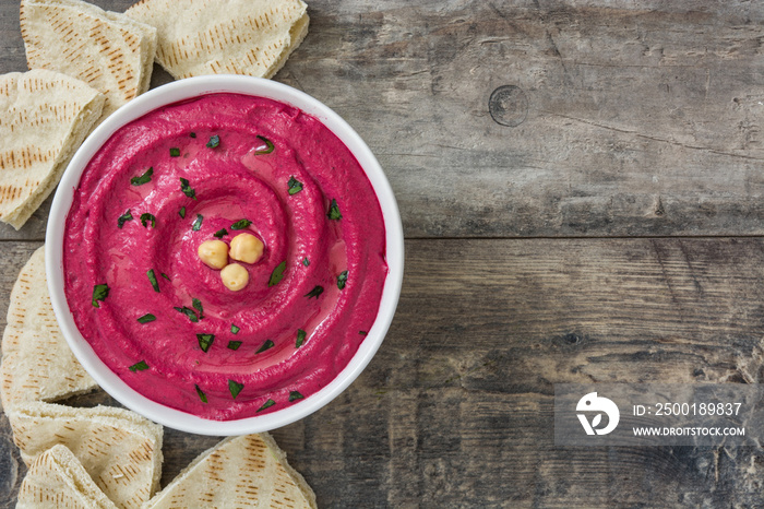 Beet hummus in bowl  on wooden table background