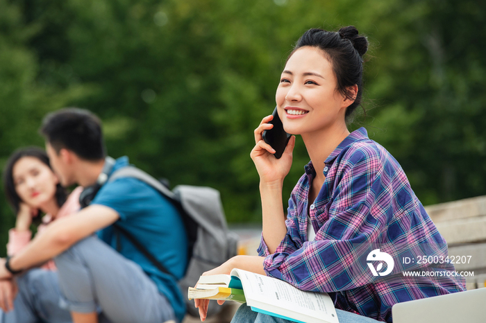 快乐的大学生坐在台阶上打电话