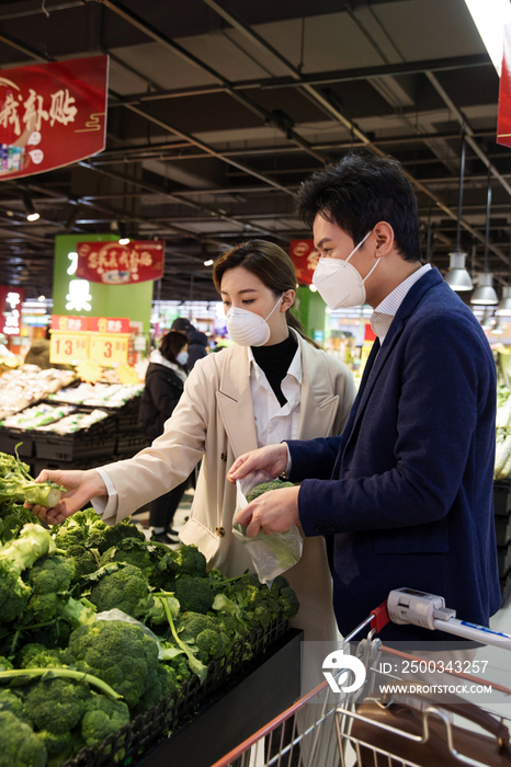 青年夫妇戴口罩在超市挑选蔬菜