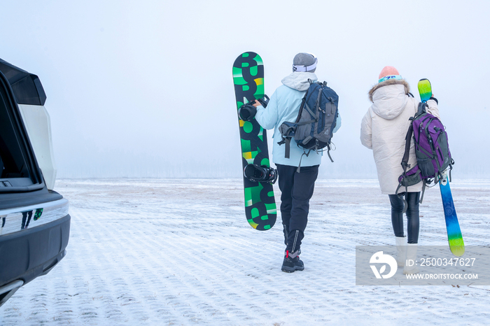 青年伴侣拿着滑雪板的背影