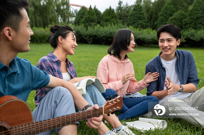 快乐的大学生在草地上弹吉他唱歌