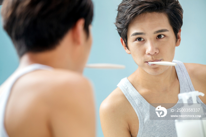 年轻男人对着镜子在刷牙