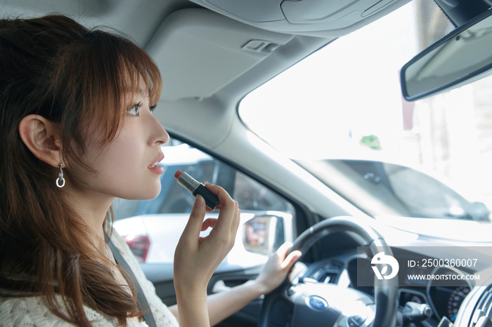 青年女人在汽车里化妆