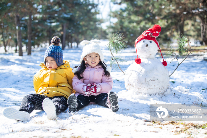 坐在雪地上玩耍的儿童和雪人