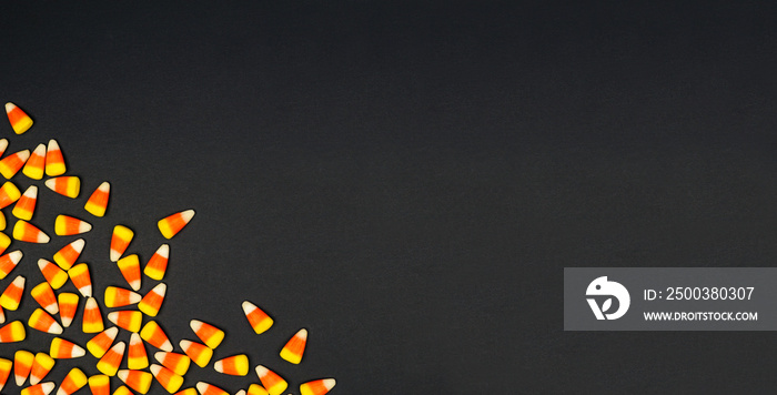 Halloween candy corn corner border banner. Top view on a black background with copy space.