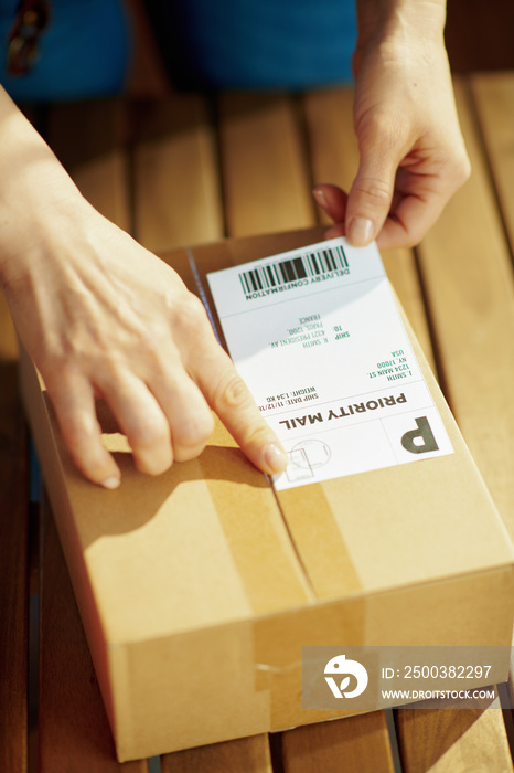 Modern woman in office applying shipping label to parcel