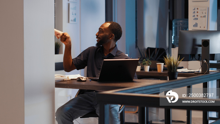 Office employee working on presentation late at night, creating professional startup report to devel