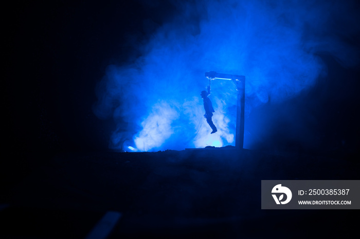 Horror view silhouette of hanged man on scaffold at night with fog and toned light on background. Ex