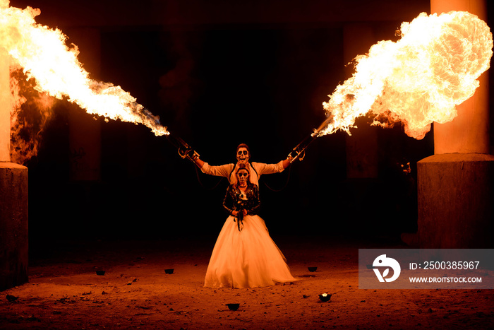 Halloween couple standing with flamethrower in hands. big fire