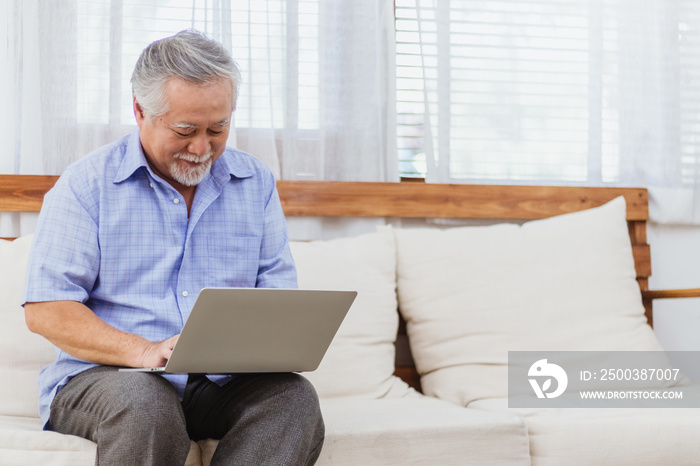 Happy healthy Asian senior elderly man working on computer at home. Retired grandfather enjoy learni