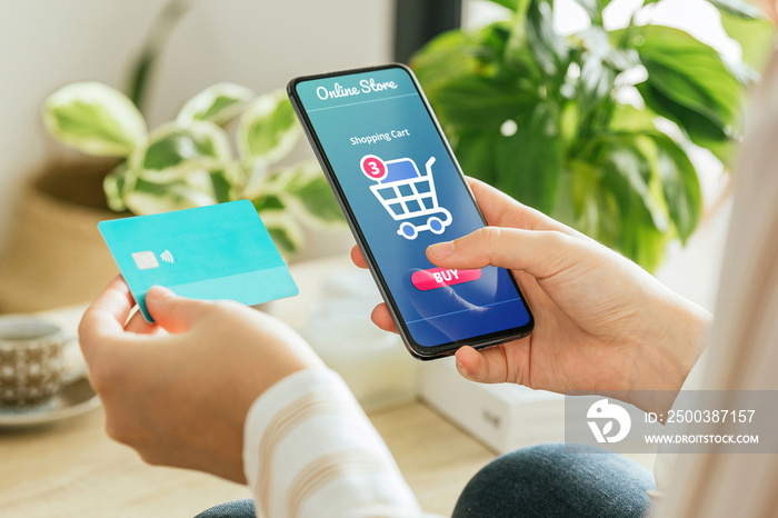 Mockup of a woman paying an order online with the phone and a credit card from home