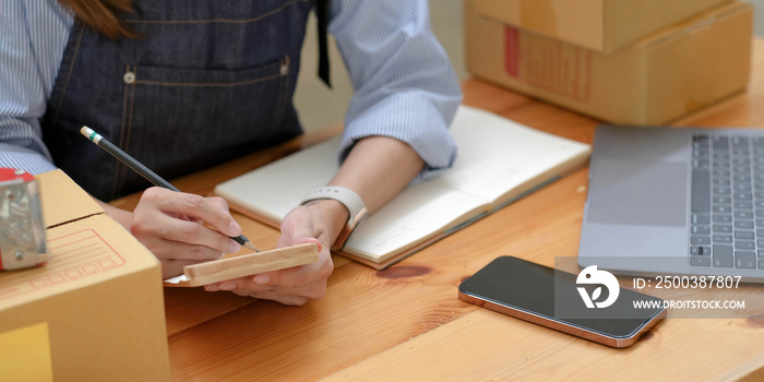 Shipping shopping online ,young start up small business owner writing address on cardboard box at wo