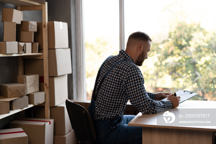 . the business owner sits at the desk and checks the order for confirmation before sending the custo