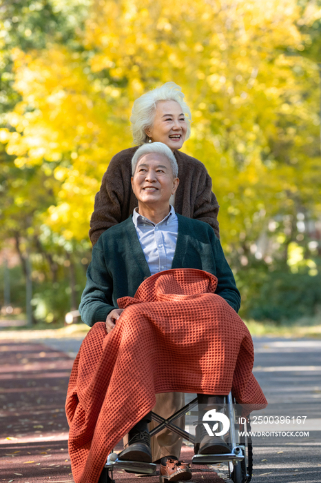 老年女人推着坐轮椅的老伴散步