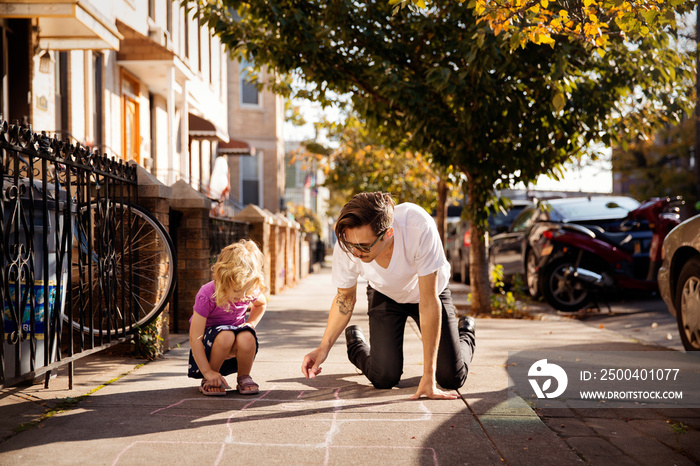 Father and daughter drawing on pavement