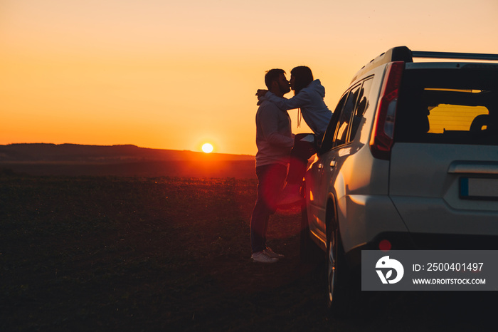 romantic moment couple kissing on sunset near white suv car