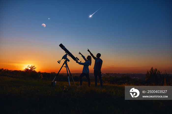 Couple stargazing together with a astronomical telescope.