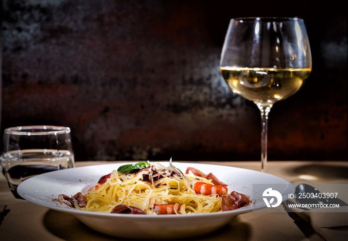 在美味的意大利面附近放一杯葡萄酒，配虾、磨碎的奶酪、果酱、番茄酱和