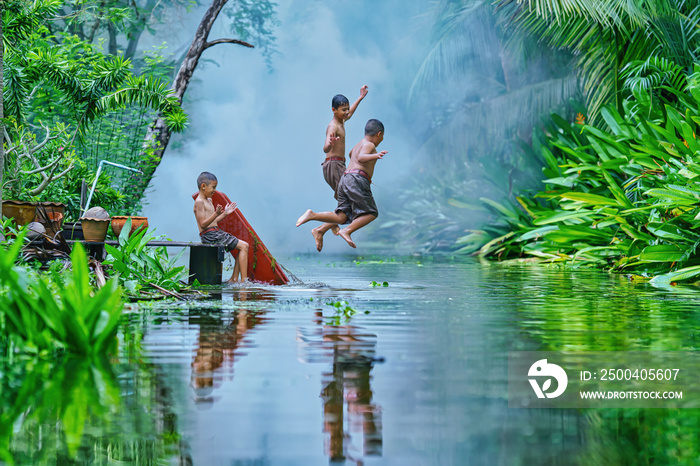 three local thai boys enjoying jumping water in canal together