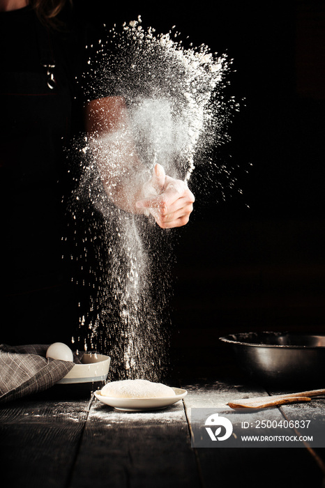 Baker hands sprinkling with flour pizza preparation