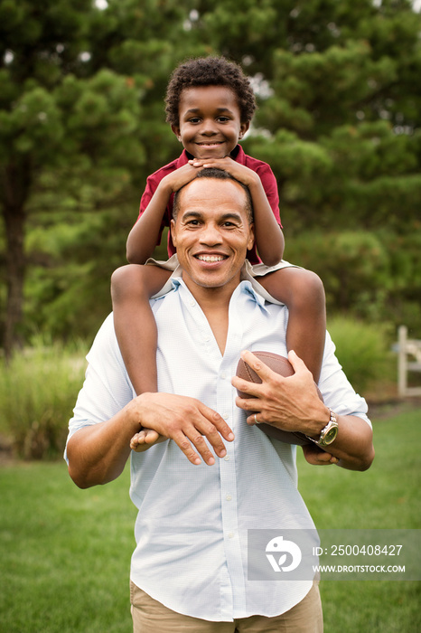 Portrait of smiling father giving piggyback ride to his son outdoors