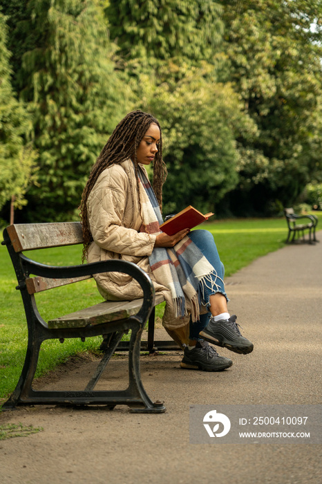 秋天公园里穿大衣的女人看书