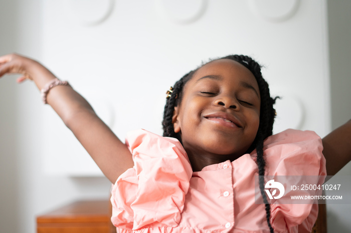 Smiling girl (6-7) throwing hands in air