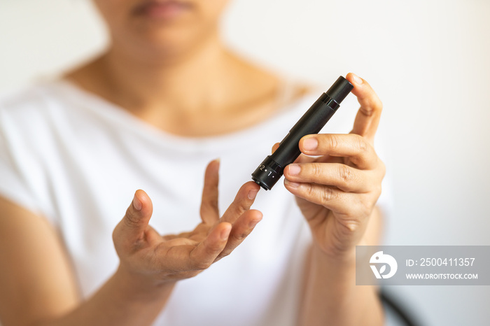 Close up of woman hands using lancet on finger to check blood sugar level by Glucose meter. Use as M