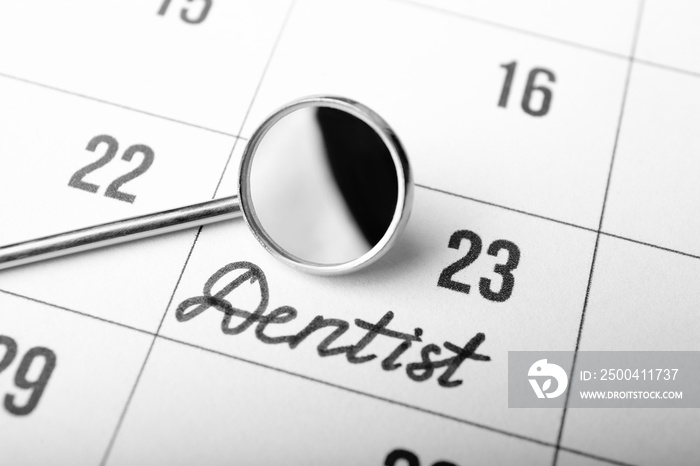 Dental mirror on calendar background