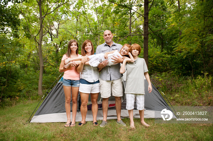 Family with three children (6-7, 12-13, 16-17) standing in front of tent