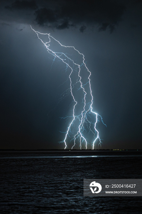 A number of lightning strikes hit the shore of a lake