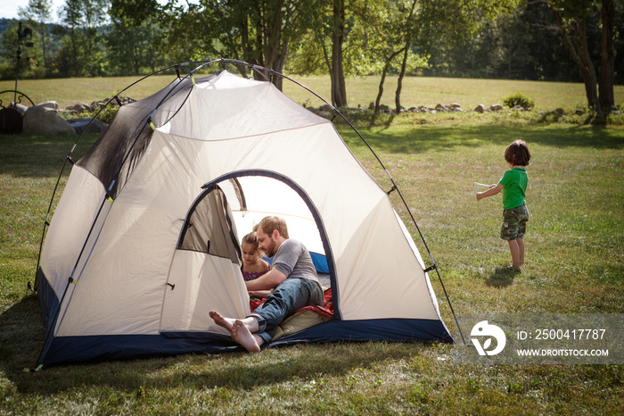 Father playing with daughters (4-5) in tent