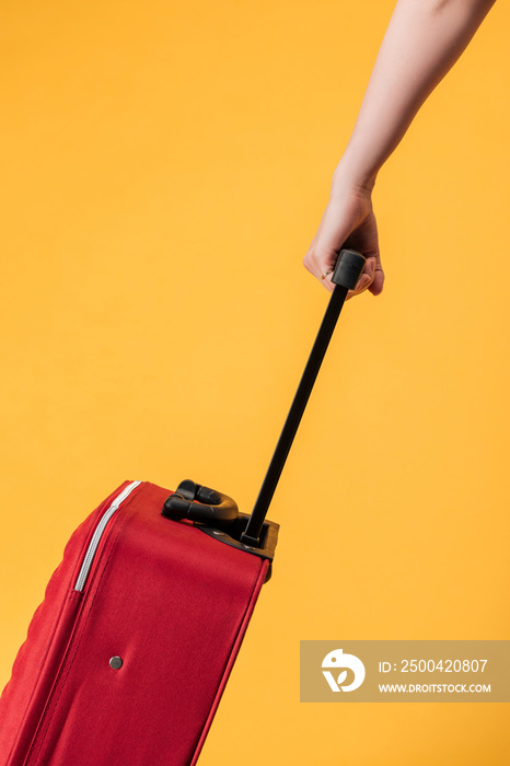 cropped view of woman with red travel bag isolated on yellow