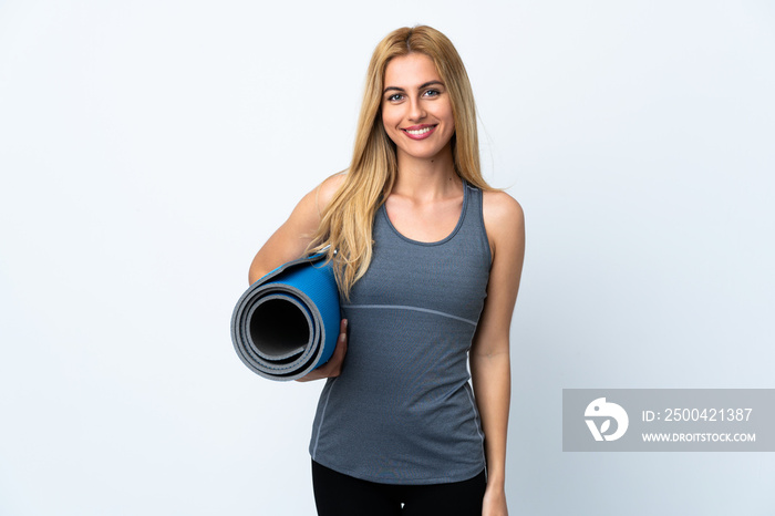 Young sport woman going to yoga classes while holding a mat over isolated white background smiling a