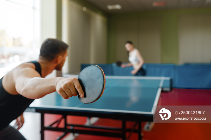 Man and woman playing ping pong, focus on racket