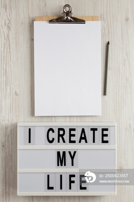 I create my life words on a lightbox, clipboard with blank sheet of paper on a white wooden surfac